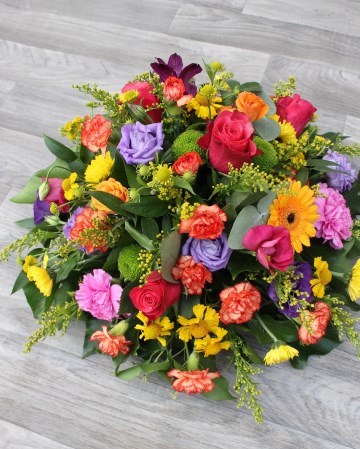vibrant posy display - funeral tribute posy design - germini - lisianthus - rose -xanths - yellow pink purple and orange flowers 
