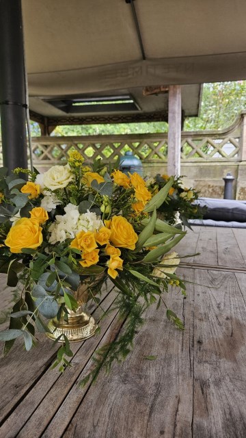 Banquette tablescape design at hampton manor for Mediterranean Shipping Company - Tall gold stands with large yellow and ivory flowers displays - short stone urns of flowers with gold and glass bud vases of flowers and gold and glass candle holders in between