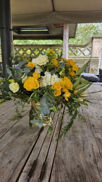 Banquette tablescape design at hampton manor for Mediterranean Shipping Company - Tall gold stands with large yellow and ivory flowers displays - short stone urns of flowers with gold and glass bud vases of flowers and gold and glass candle holders in between