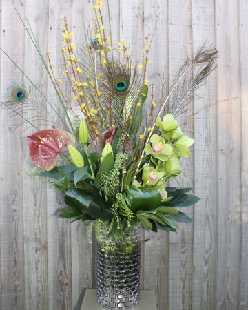 Vase Display Of Cymbidium Orchid, Lily, Anthurium, Forsythia and Peacock Feathers With Foliage  