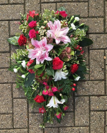 pink cerise and red single ended spray funeral tribute design - pink double lily - cerise rose and spray rose - red rose and alstromeria - ivory carnation and waxflower 