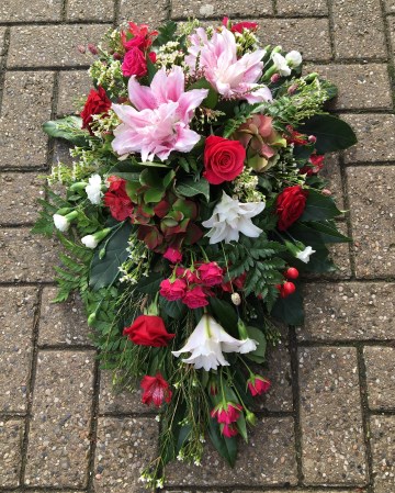 pink cerise and red single ended spray funeral tribute design - pink double lily - cerise rose and spray rose - red rose and alstromeria - ivory carnation and waxflower 