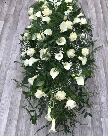ivory rose and calla lilly casket spray with mixed foliages and trailing fern - white funeral tribute design 