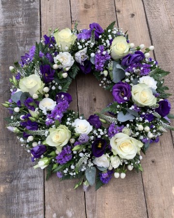 mixed blue and white wreath with ivory roses gypsophilia and purple lisianthus and statice
