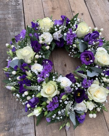 mixed blue and white wreath with ivory roses gypsophilia and purple lisianthus and statice