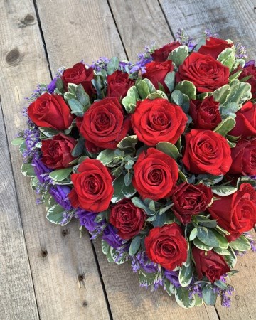 full heart of red oses with a purple lisianthus boarder and mixed foliage