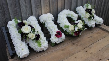 Name Funeral Tribute based in white chrysanthemum with foliage edge, white rose and cut Pansy flowers